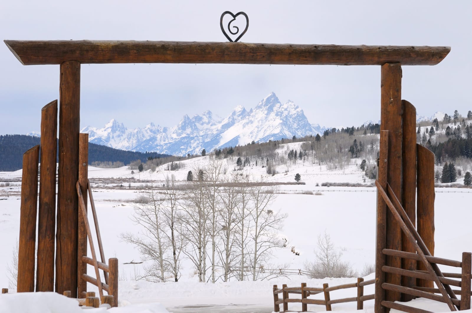Log ranch entryway framing snow-capped Montana mountains